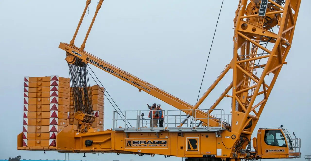 Large orange Bragg Crane Service crane with a worker on top.