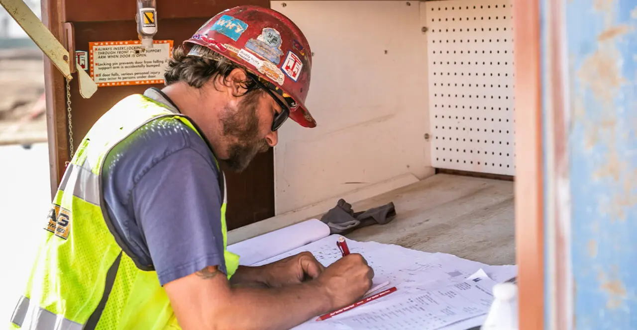 Construction worker reviewing blueprints on a construction site.