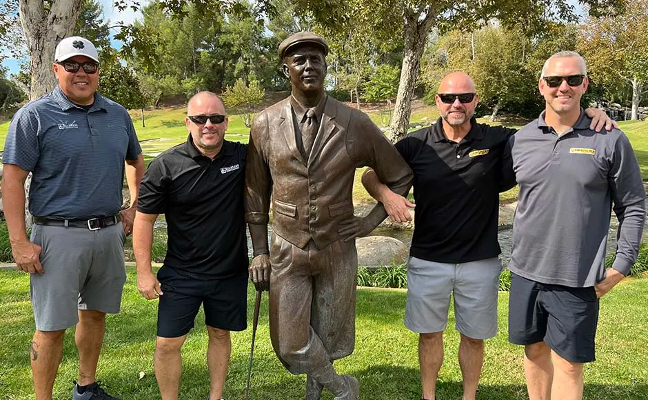 Group of men posing with a statue of a golfer.