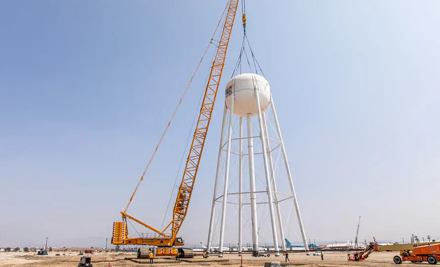 Crane lifting the water tower tank into place.